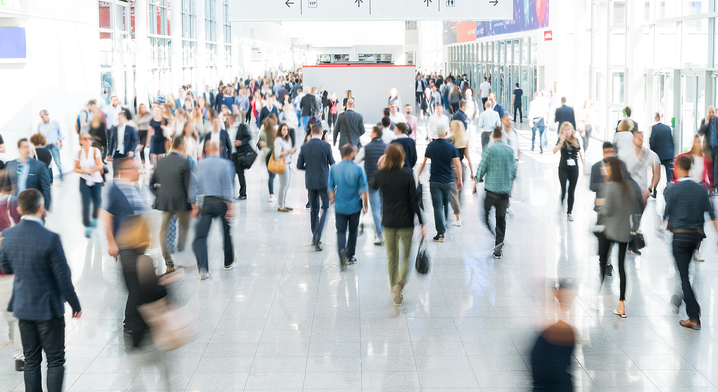 A crowd of people wandering around a trade show